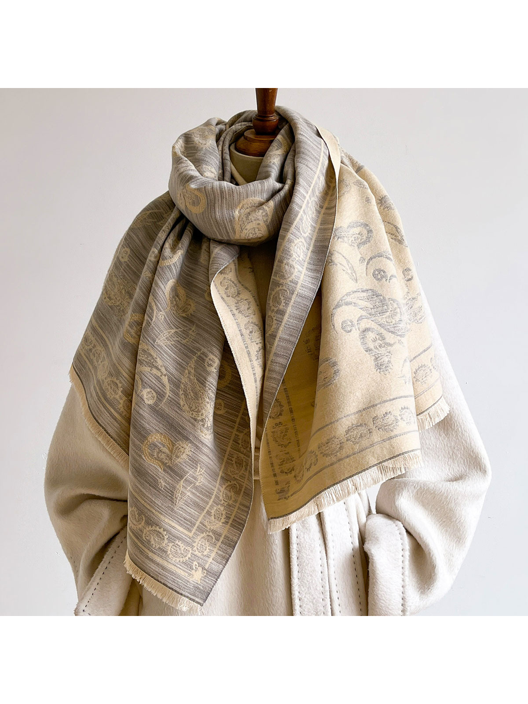 Light Gray paisley scarf looped at the neck with its cream reverse visible