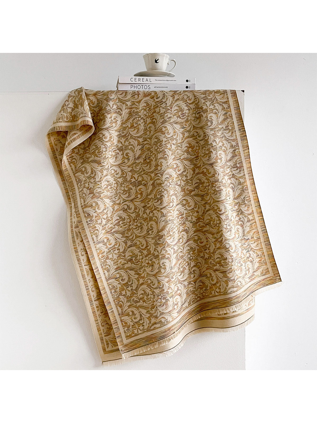 Khaki scarf with scrolling leaf pattern, striped border and short fringe, draped open.