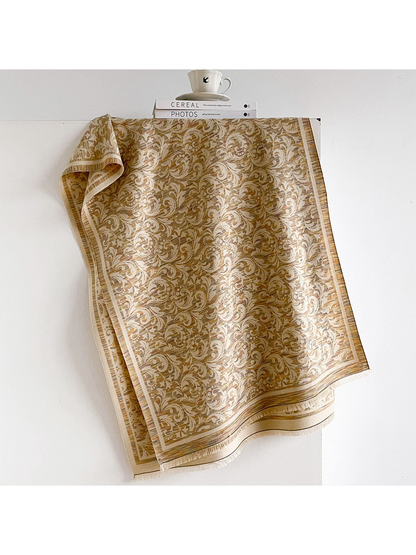 Khaki scarf with scrolling leaf pattern, striped border and short fringe, draped open.