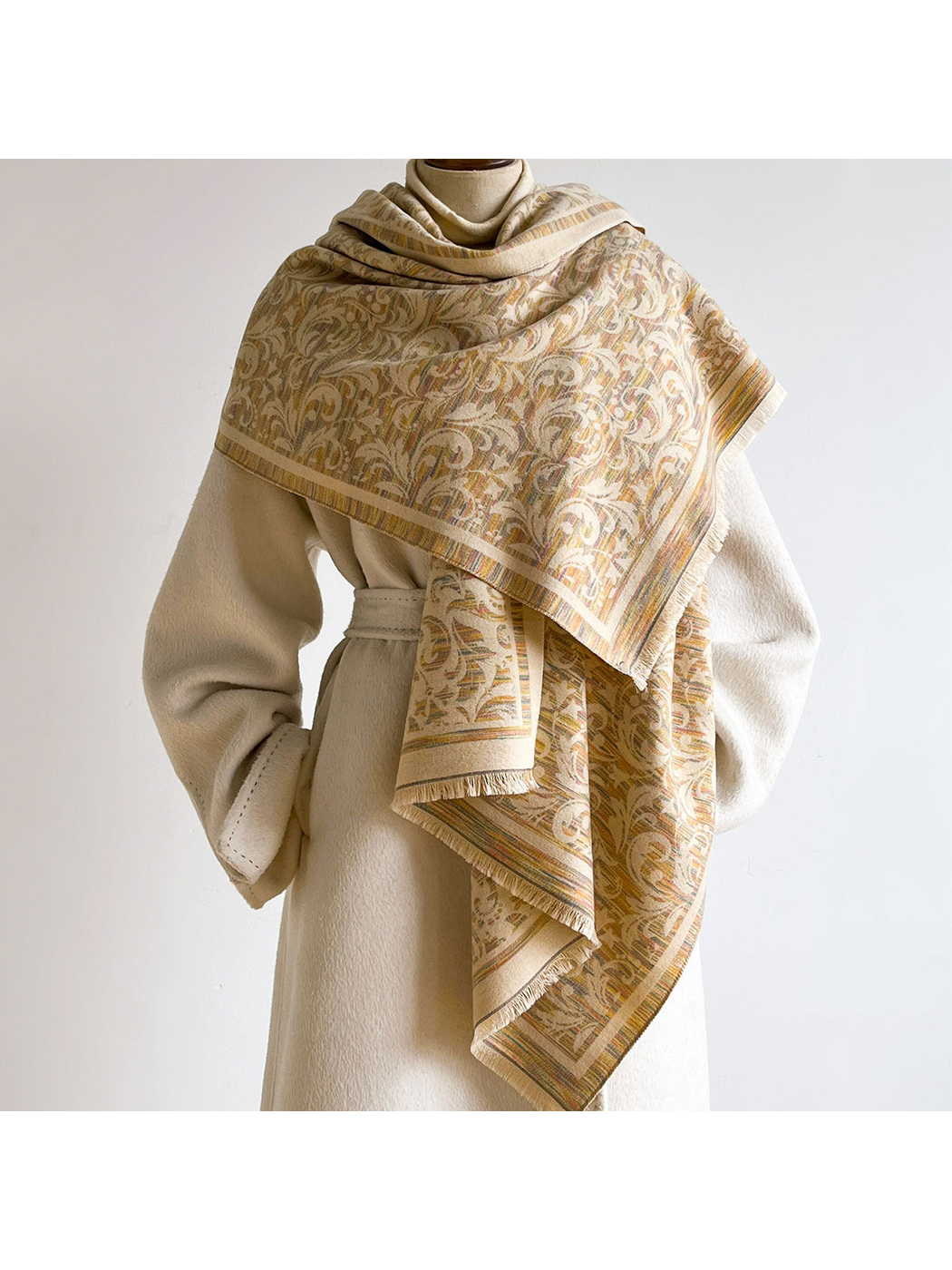 Khaki patterned scarf wrapped across the shoulders of a mannequin wearing a cream coat.