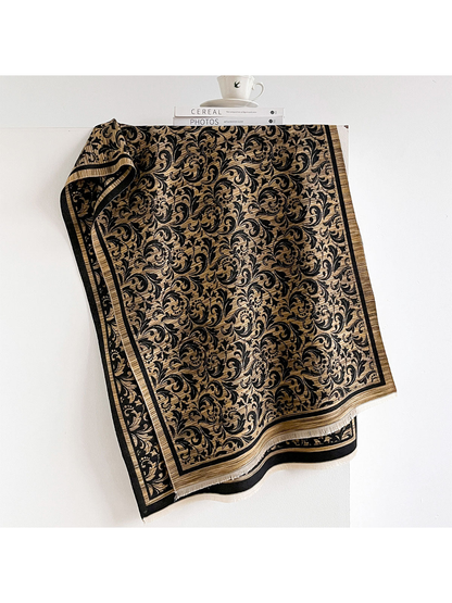 Black / Gold scarf with scrolling leaf pattern, striped border and short fringe, draped open.