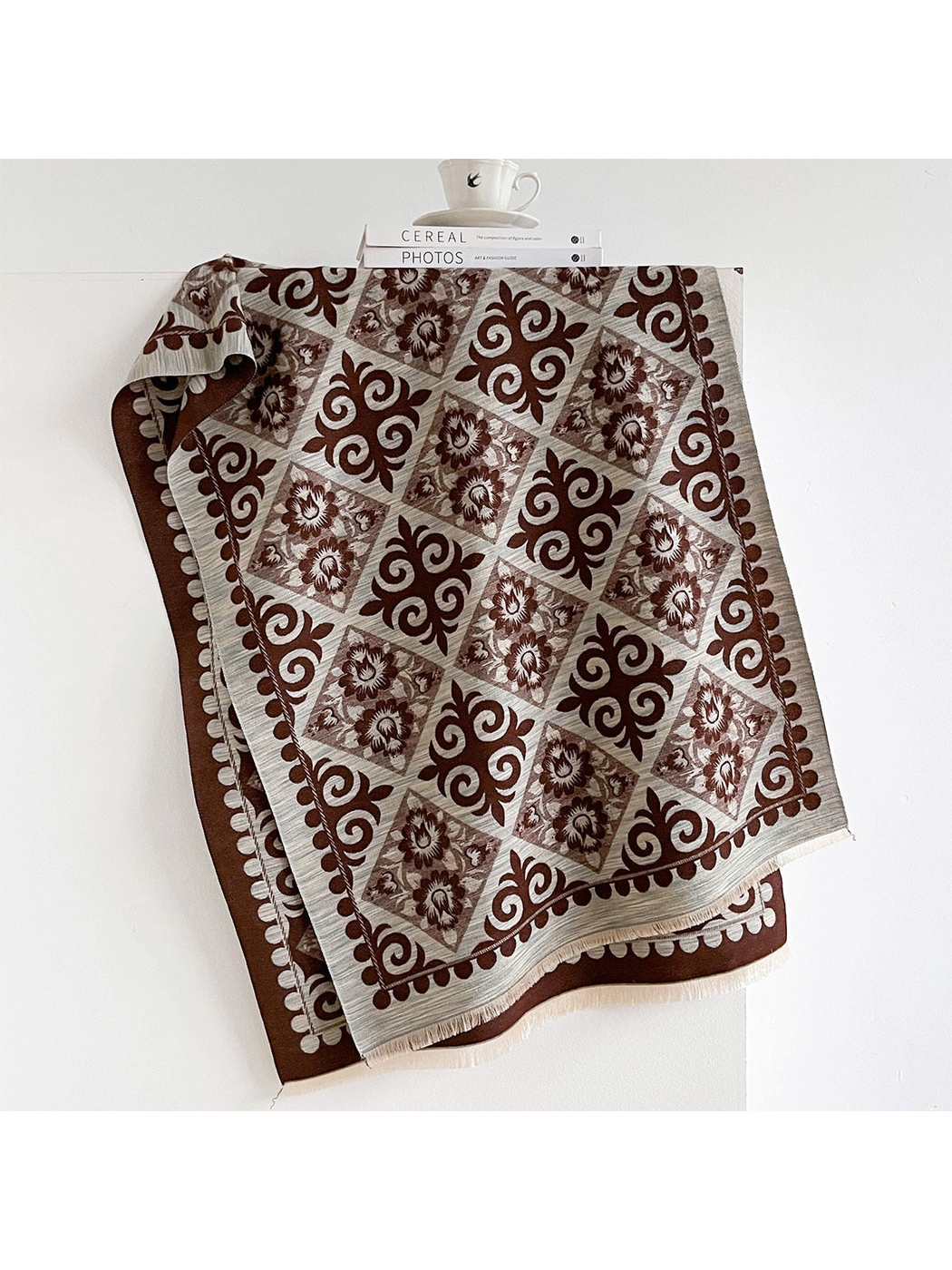 Coffee scarf draped open with contrasting floral diamonds, ornamental scrolls, a patterned border and short fringe.