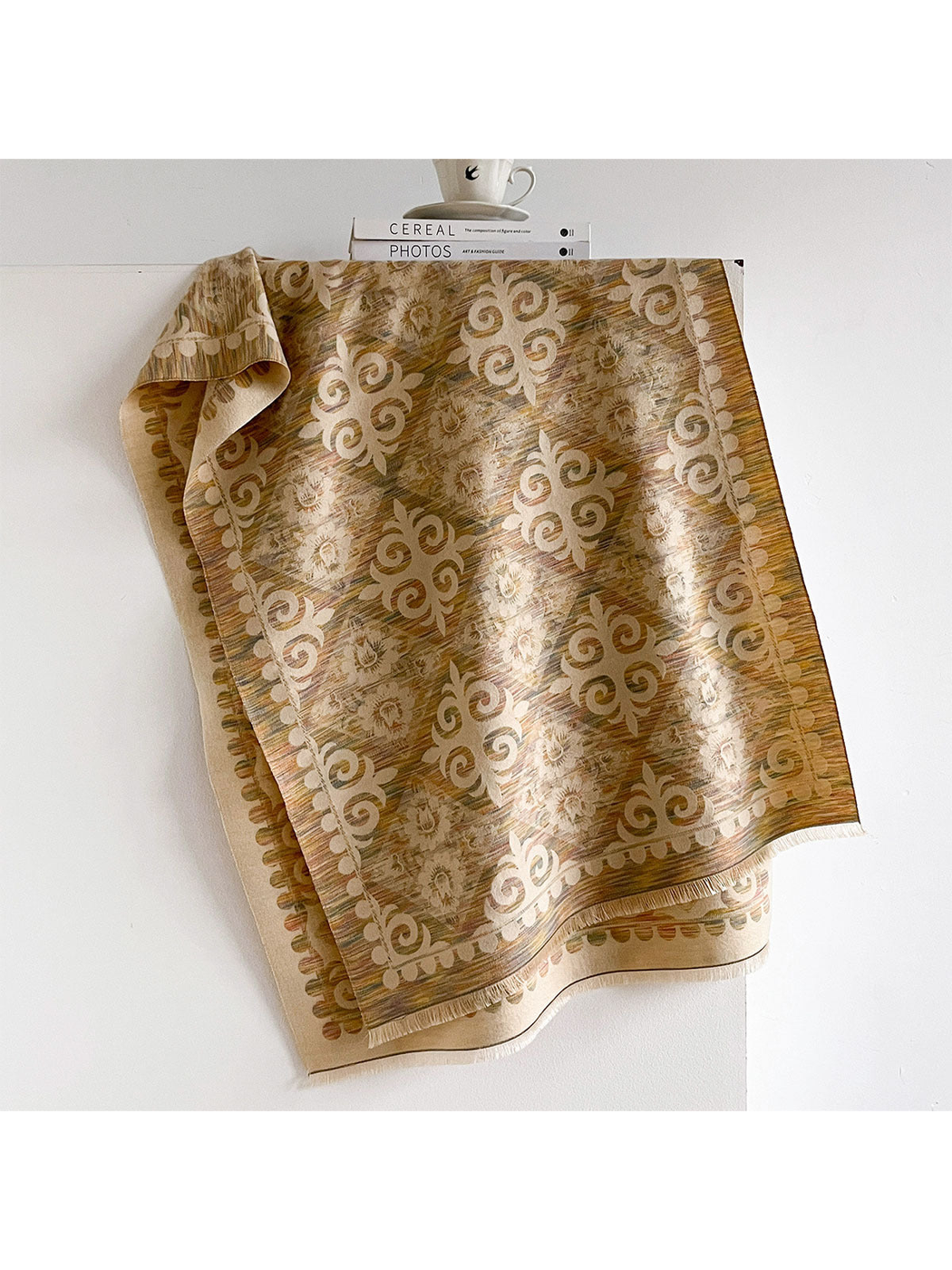 Multicolor scarf draped open with muted colored streaks, cream floral and scroll motifs, and short fringe.