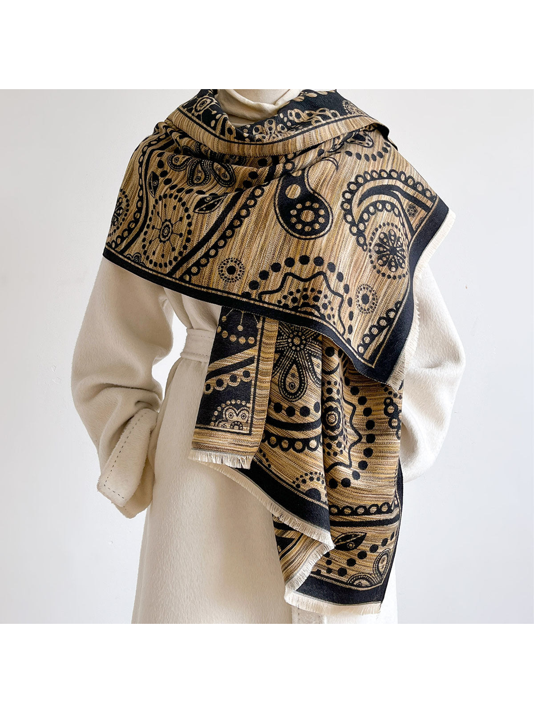 Black / Gold paisley scarf wrapped across the shoulders of a mannequin wearing a cream coat.