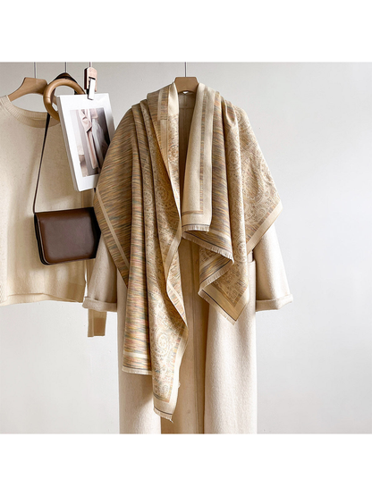Multicolor paisley and striped scarf draped over a hanging cream coat beside a sweater and brown bag.