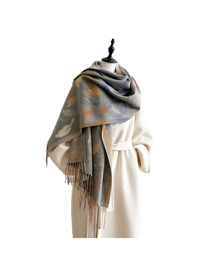 Gray feather-pattern scarf wrapped around a mannequin over a cream coat, with fringed ends hanging down.