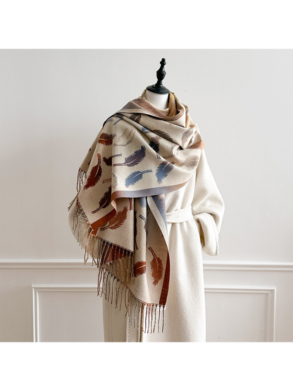 Cream feather-pattern scarf draped broadly over a mannequin's shoulders with fringed ends hanging in front.