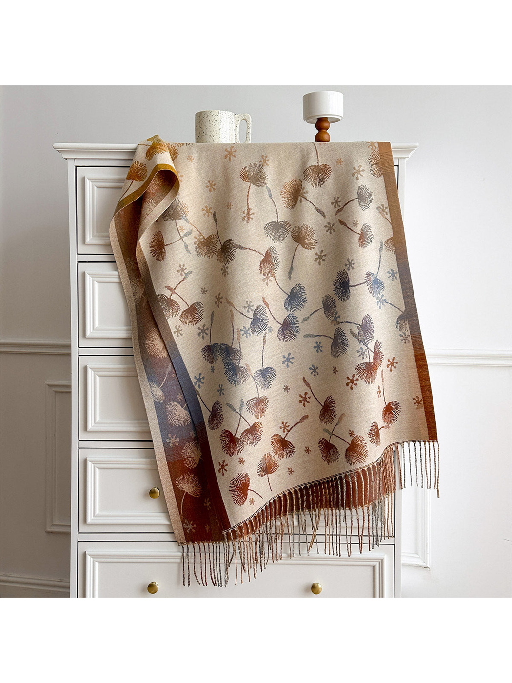 Ivory floral scarf draped over a white chest, with contrasting borders and long fringe.