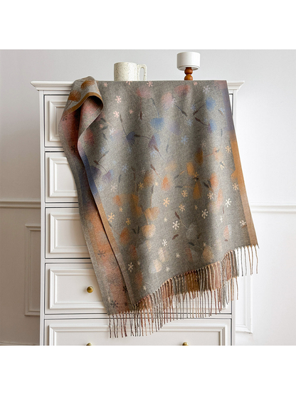 Gray floral scarf with contrasting borders and twisted fringe, draped over a white chest.
