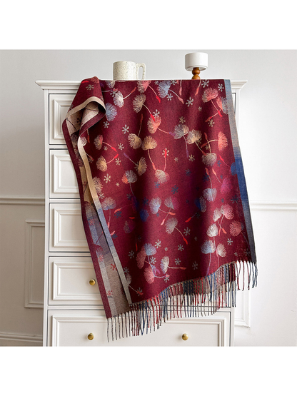 Burgundy floral scarf with multicolored borders and long fringe, draped over a white chest.