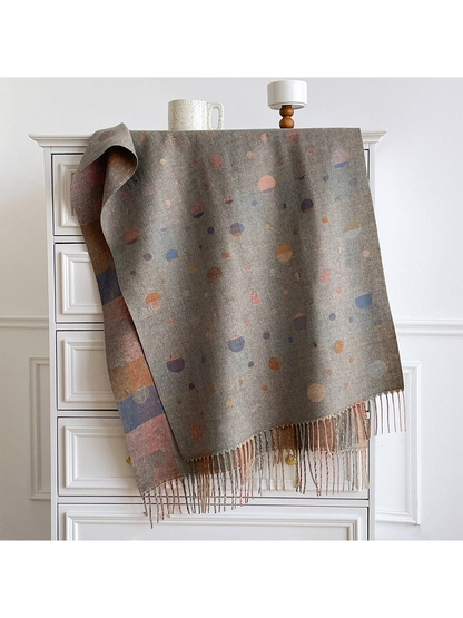 Gray scarf with multicolored polka dots, draped over a cabinet with fringe and a contrasting reverse visible.