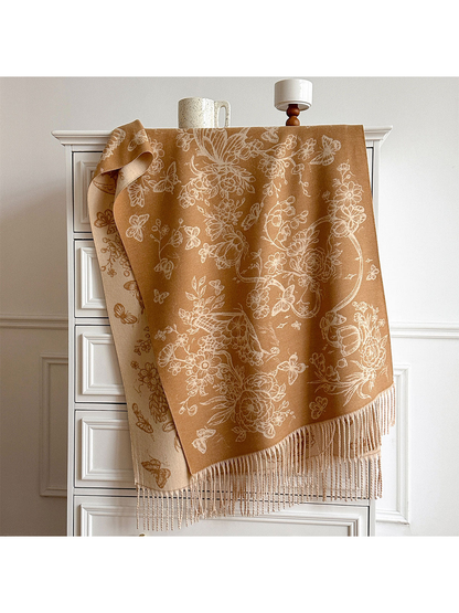 Caramel scarf with cream floral and butterfly motifs draped over a cabinet, showing its contrasting reverse and fringed ends.