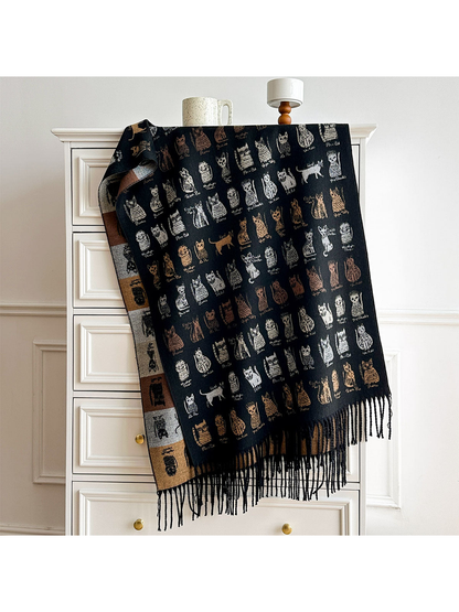 Black cat-pattern scarf draped over a dresser, showing its contrasting reverse and black fringe.