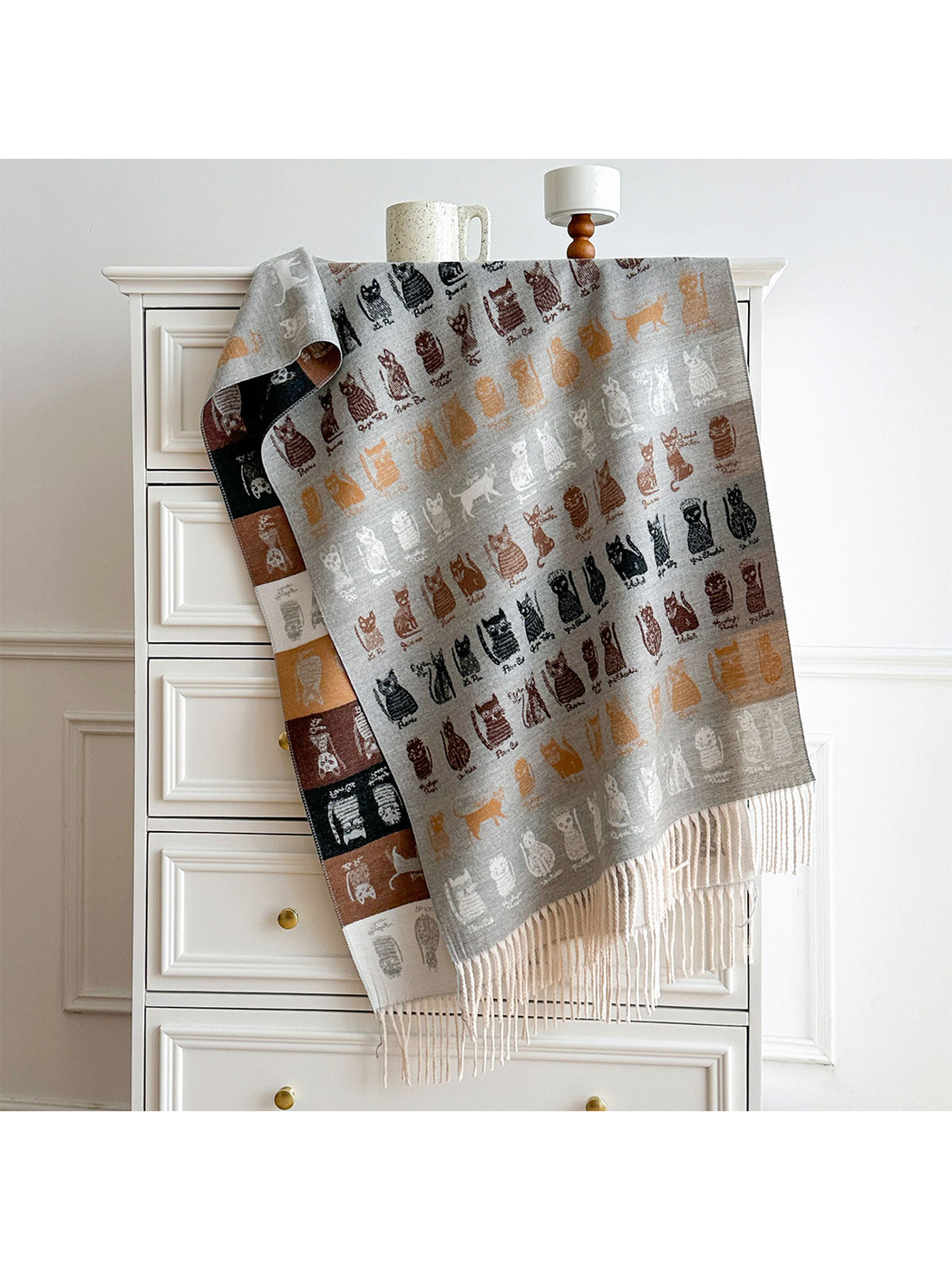 Light Gray cat-pattern scarf draped over a dresser, with a contrasting color-block reverse and pale fringe.