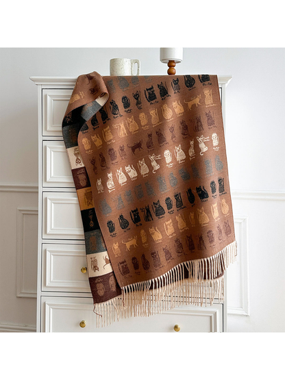 Brown cat-pattern scarf draped over a dresser, showing its contrasting reverse and pale fringed ends.