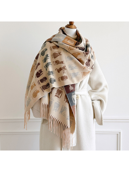 Beige cat-pattern scarf draped broadly around a mannequin's shoulders over a white coat, with fringe hanging in front.