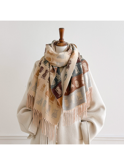 Beige cat-pattern scarf looped around a mannequin's neck, with long ends displaying both patterned sides over a white coat.