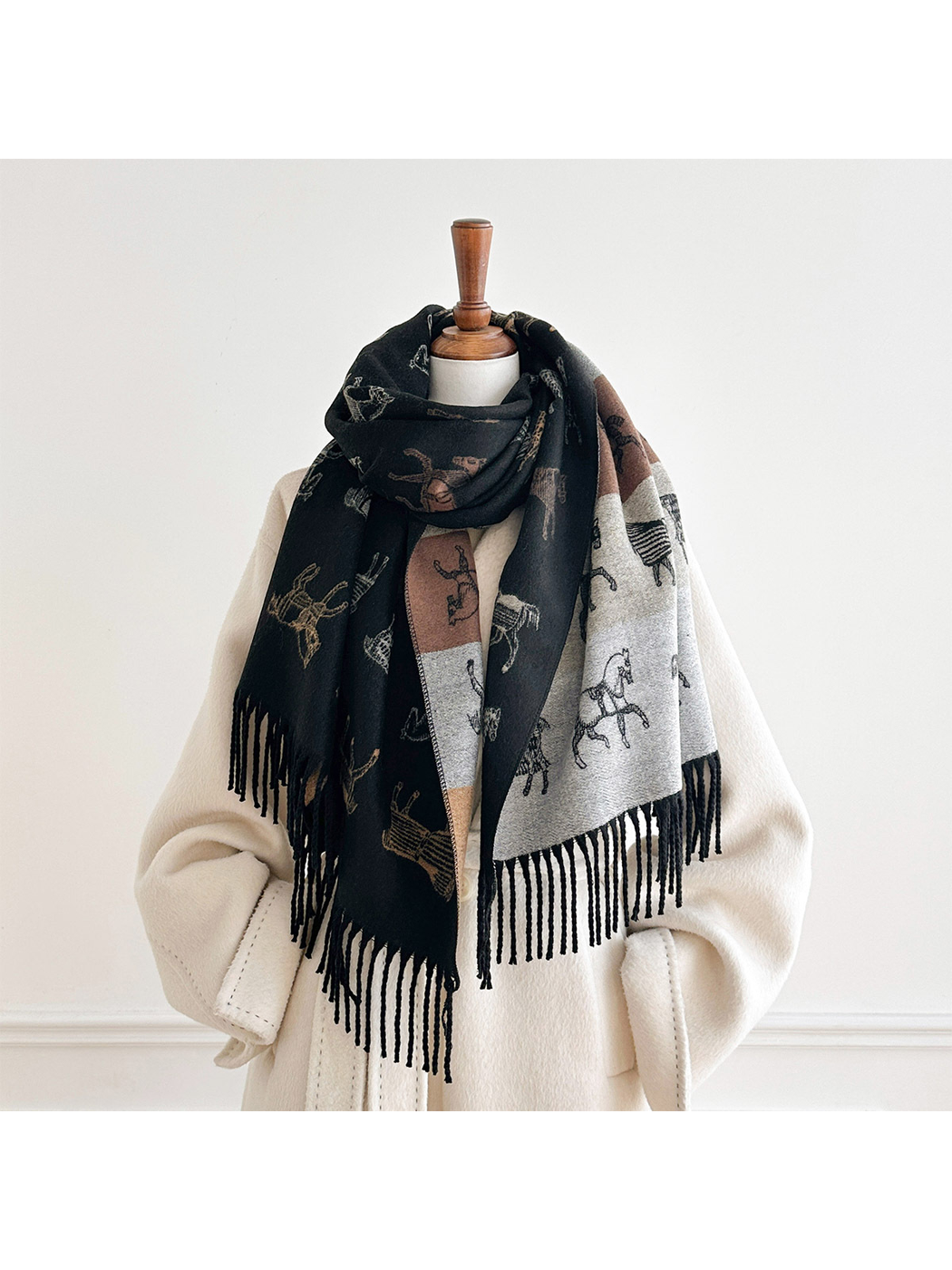 Black horse motif scarf looped around a mannequin's neck, with both fringed ends and the contrasting reverse visible.