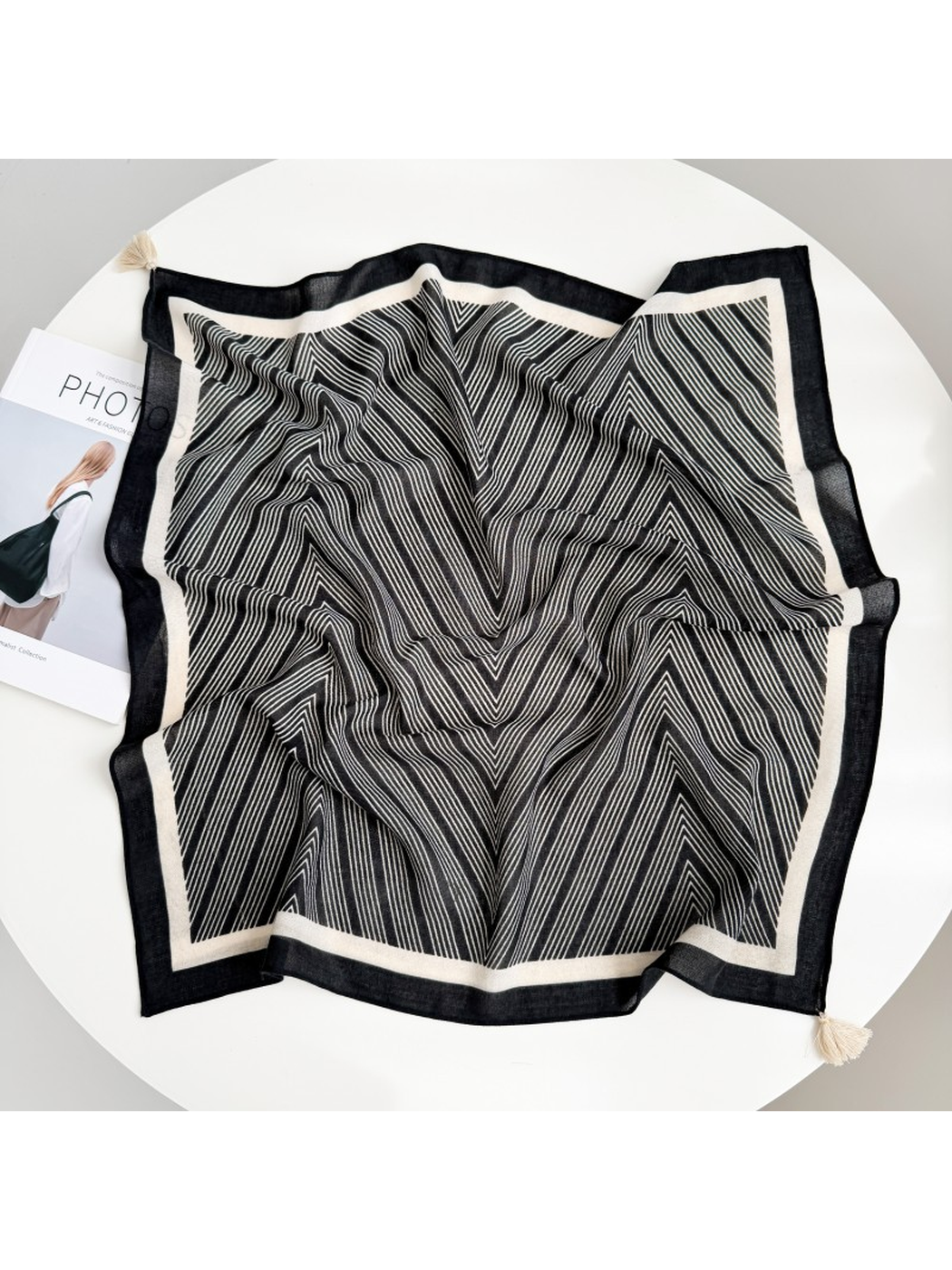 Black square scarf spread out with fine ivory chevrons, contrasting borders and ivory corner tassels.