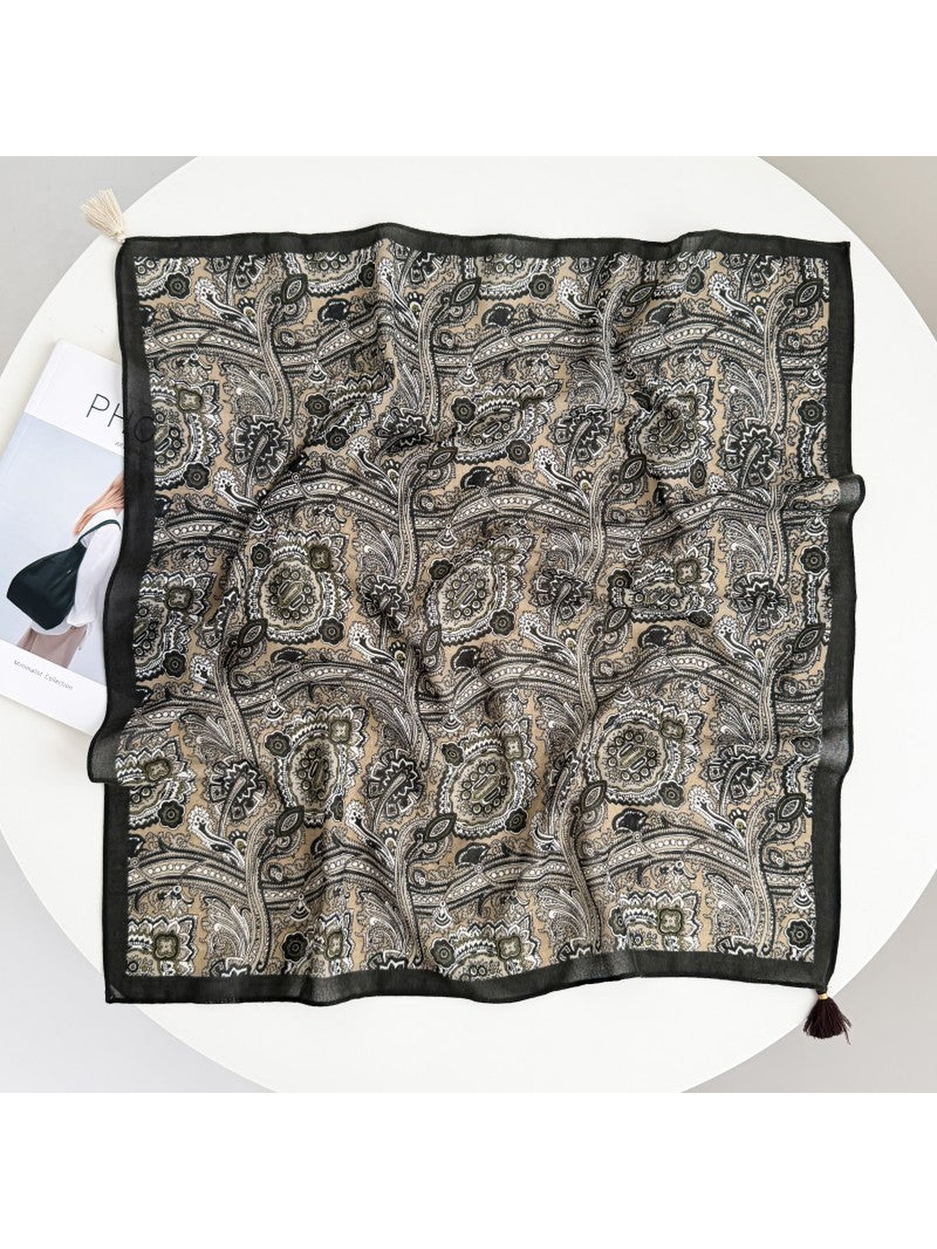 Square paisley scarf spread flat with a dark border and cream and dark brown tassels at opposite corners.