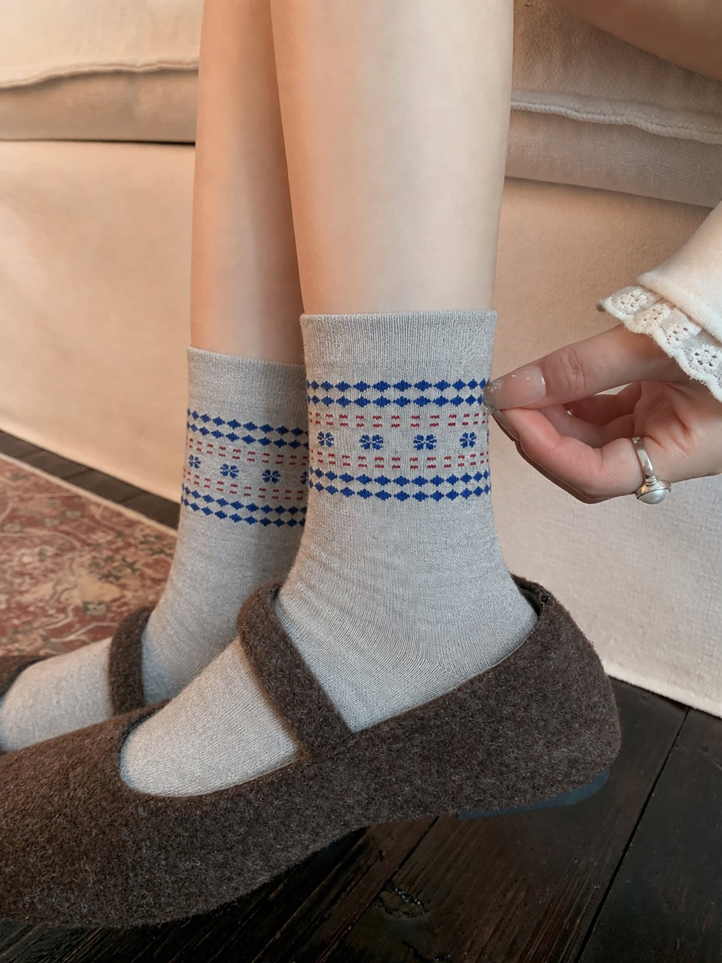 Heather gray Geometric Flowers socks with blue patterned bands and red dashes worn with brown strap shoes.