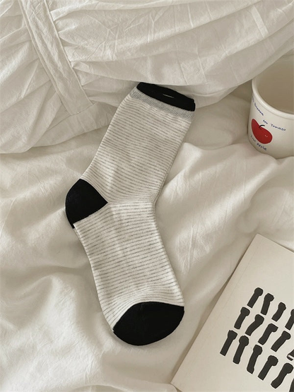 White striped crew sock with black cuff trim, heel and toe, laid flat.