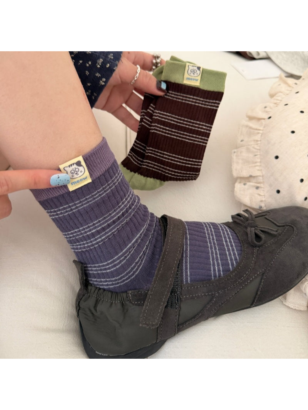 Navy / Purple striped sock worn with a dark shoe while a Brown / Green sock is held beside it.