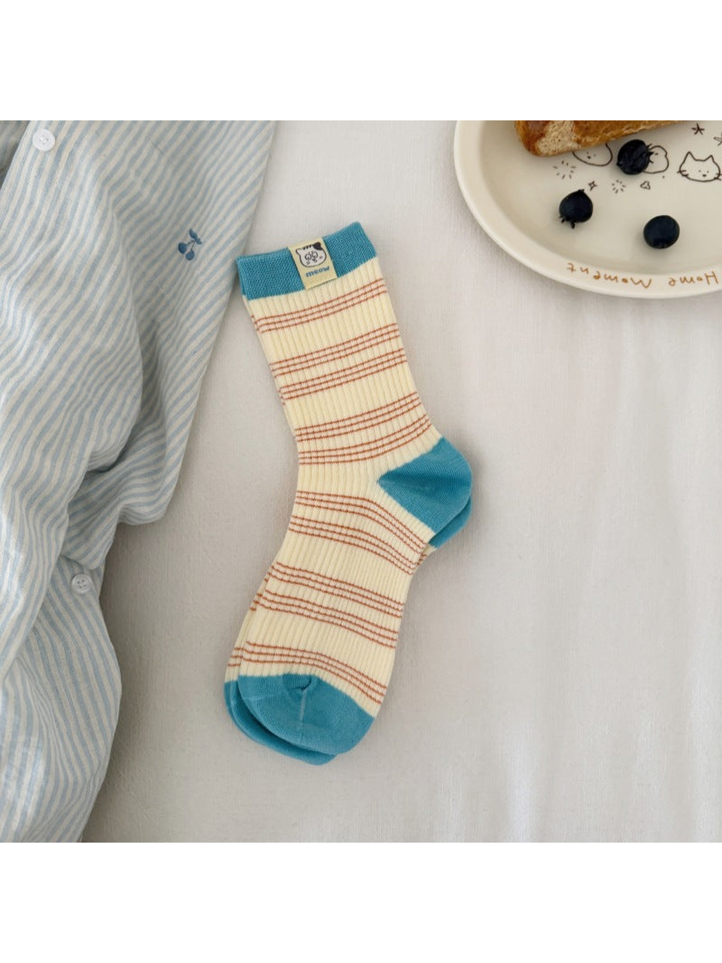 Cream / Turquoise striped ribbed socks laid flat with contrasting cuff, heel and toe panels and a cat label.