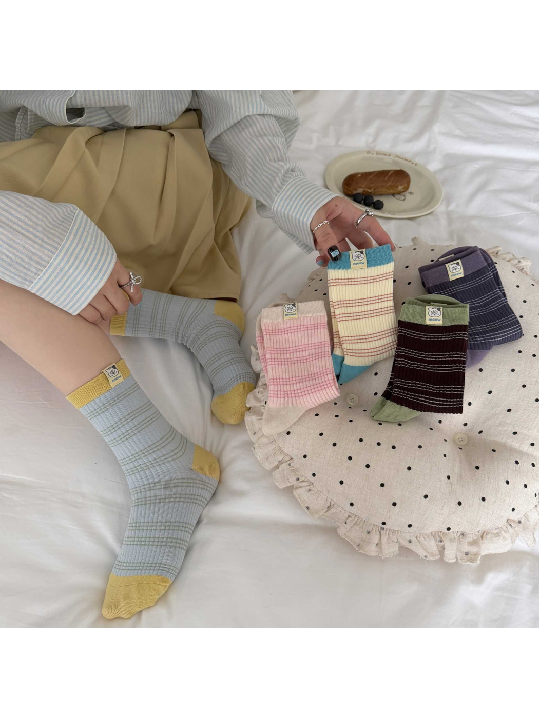 Blue / Yellow striped socks worn without shoes beside four other sock colors arranged on a dotted cushion.
