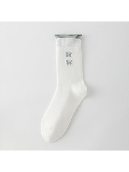 White crew sock with a gray rolled upper edge and two gray bow motifs.