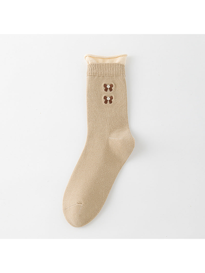 Beige crew sock with a cream rolled upper edge and two brown bow motifs.