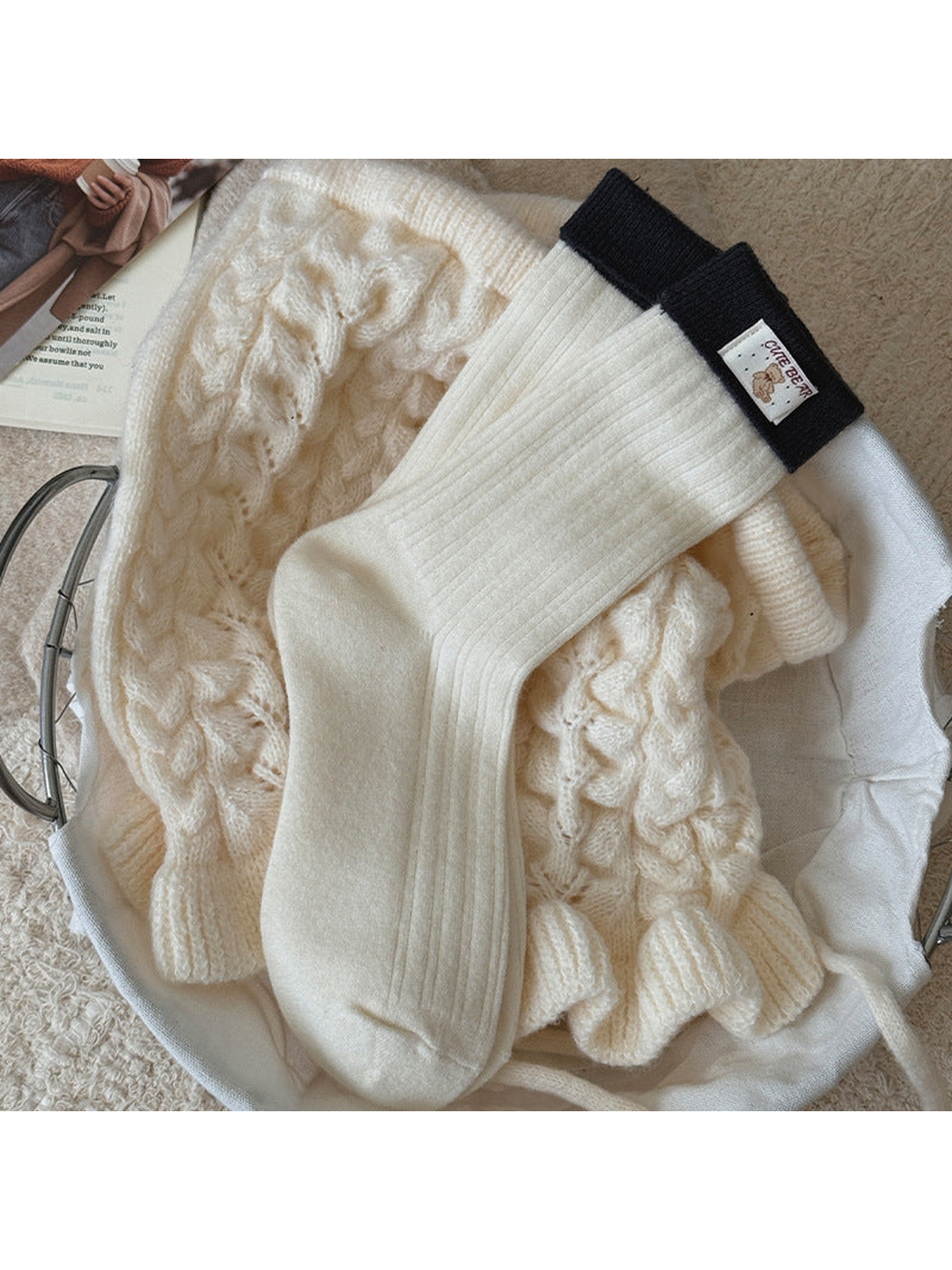 Ivory ribbed socks with dark navy folded cuffs and a bear label, laid flat.