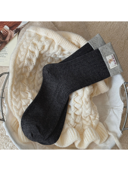Black Gray ribbed socks with light gray folded cuffs and a bear label, laid flat.