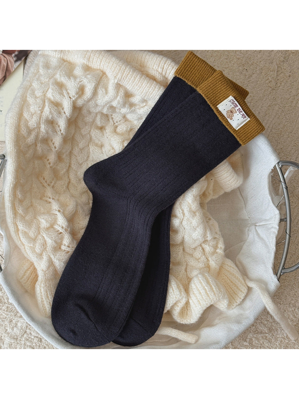 Navy ribbed socks with mustard folded cuffs and a bear label, laid flat.