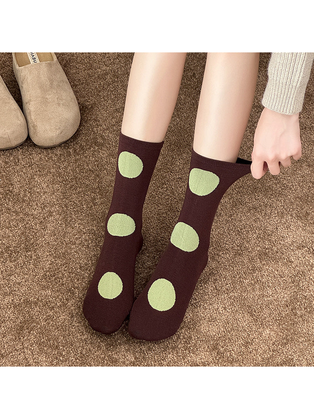 Dark Brown polka dot socks worn with one cuff pulled outward by hand.