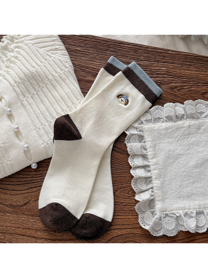 Ivory crew socks with dog faces, brown heels and toes, and blue-edged cuffs