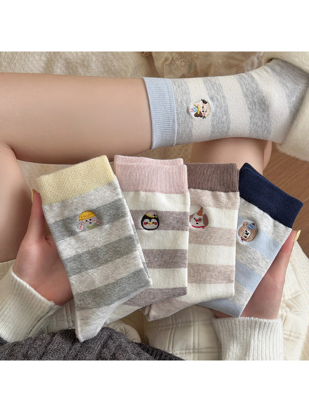 Striped socks with contrasting cuffs and animal embroidery held together beside a worn sock.