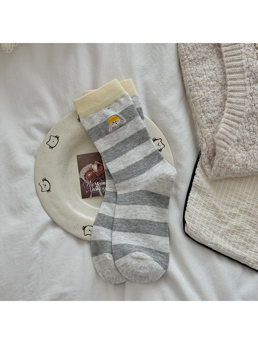 Yellow cuff socks with gray and white stripes and embroidered rabbit motifs.