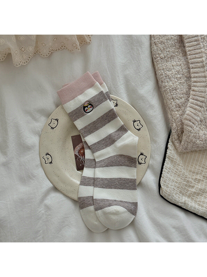 Blush cuff socks with greige and ivory stripes and embroidered penguin motifs.