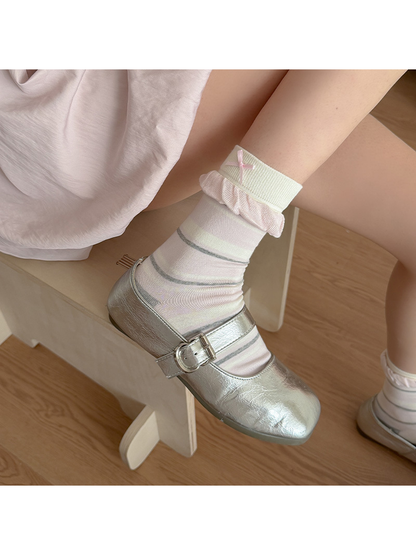 Multicolor striped sock worn with a silver-tone buckle shoe, showing a pink ruffle and small cuff bow.