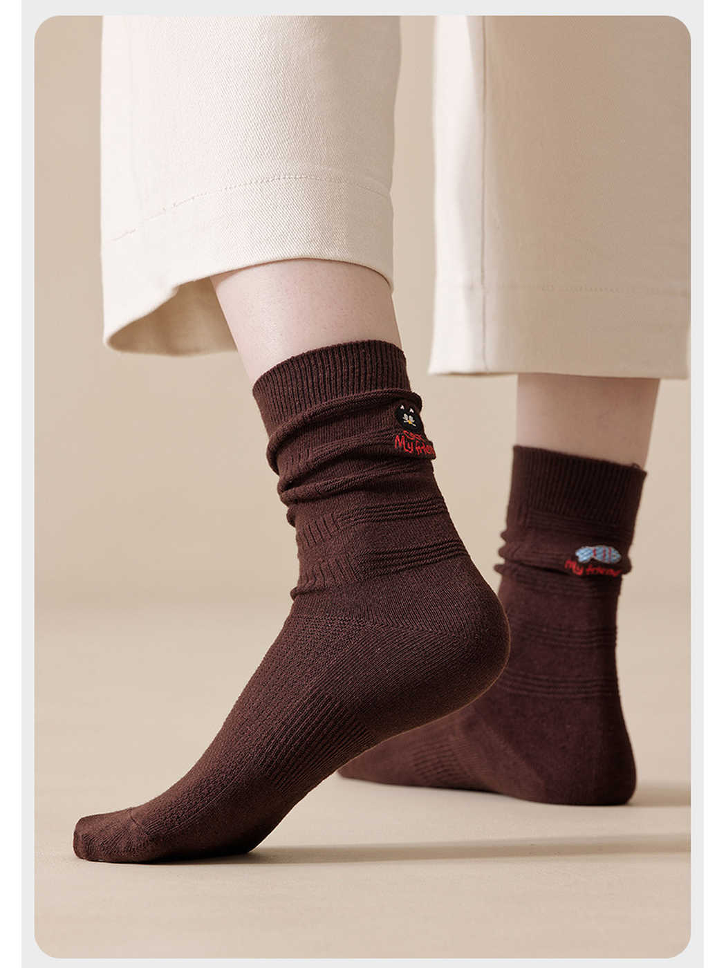 Dark Brown embroidered socks worn with cream cropped pants, with one heel raised.