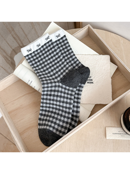 Gingham socks with gray and white checks, small cuff bows, and dark heel and toe panels.