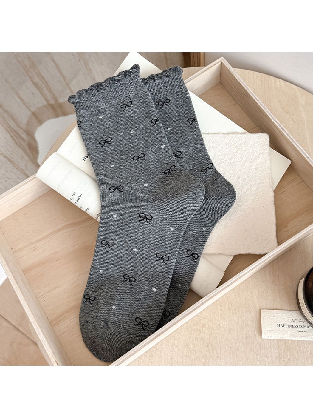Dark gray Bows socks with scattered black bows, light dots and ruffled cuff edges.