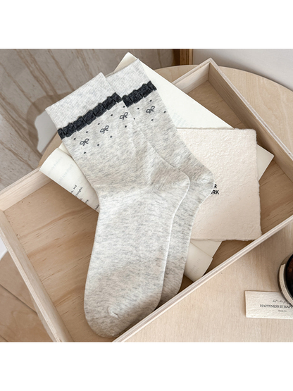 Light gray Ruffled Band socks with dark trim below the cuffs and small bow and dot motifs.