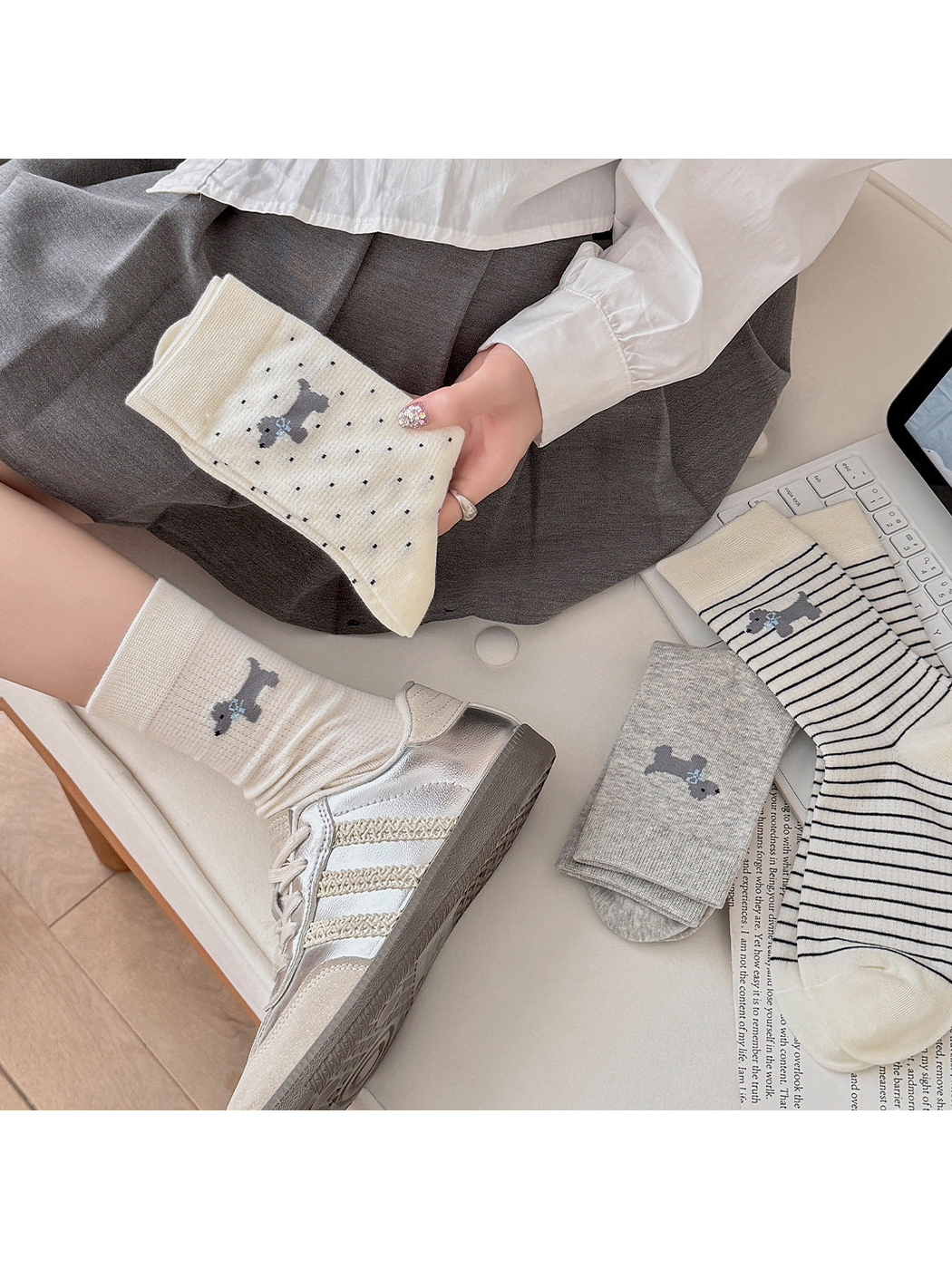 Cream dog motif socks worn with metallic-look sneakers while dotted socks are held beside folded styles.