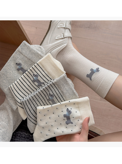 Dog motif socks in five styles, with four folded styles held beside a worn cream sock.