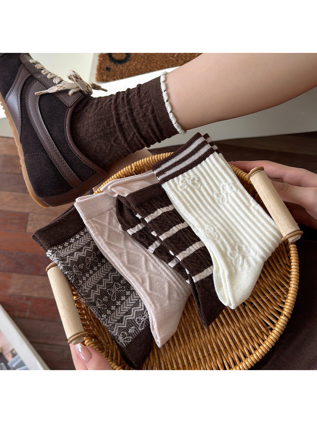 Brown scalloped-cuff socks worn with sneakers beside a basket holding folded patterned socks.