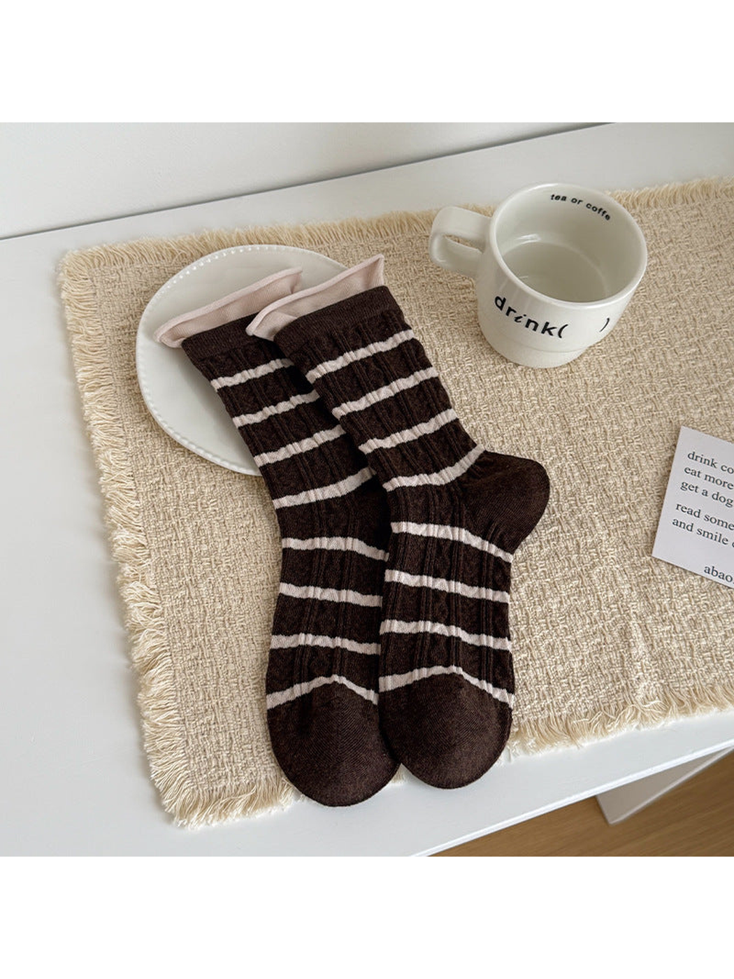 Brown Striped socks with ivory horizontal bands and contrasting inner cuffs, laid flat.