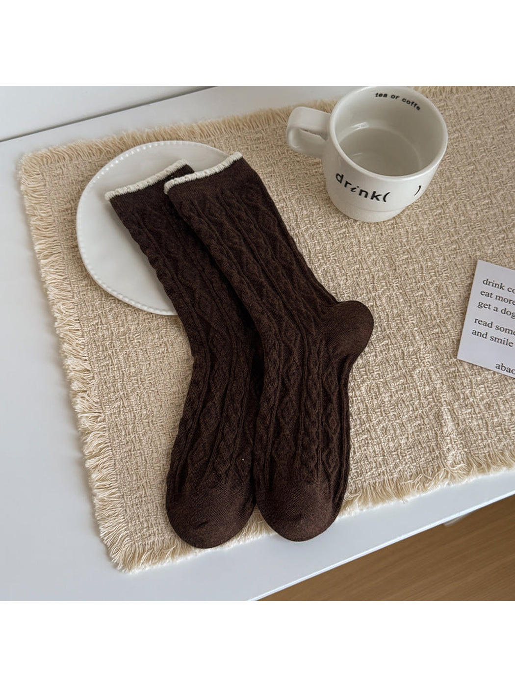 Dark brown Scalloped socks with cable texture and ivory cuff edging, laid flat.