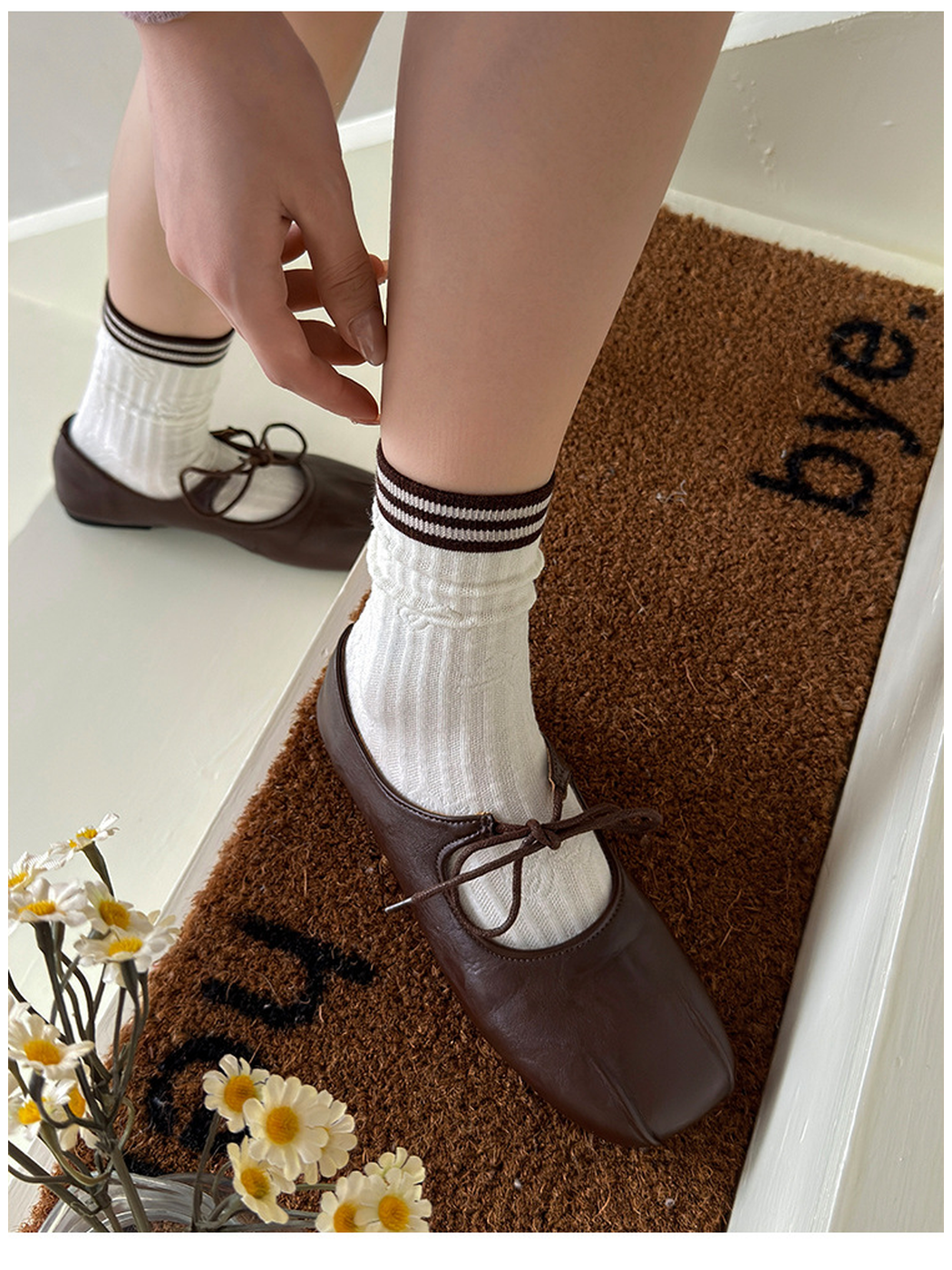 Ivory cable-pattern socks with striped cuffs worn with brown tie-front shoes on steps.